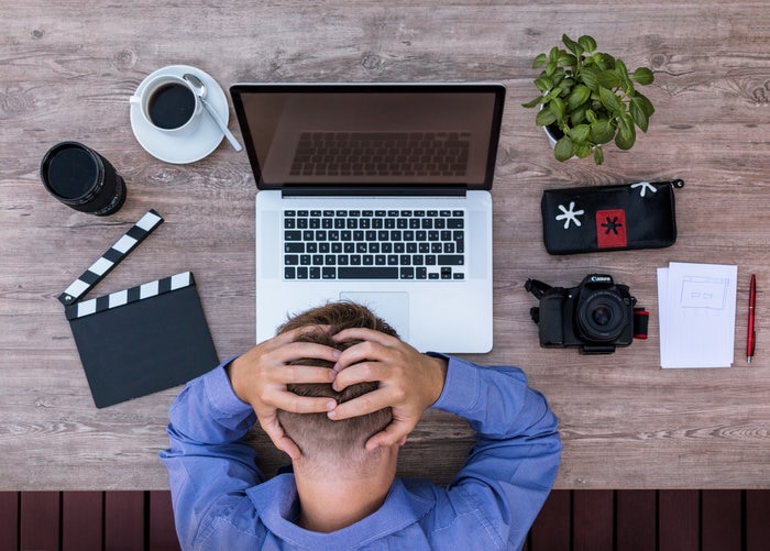 Man banging head next to laptop
